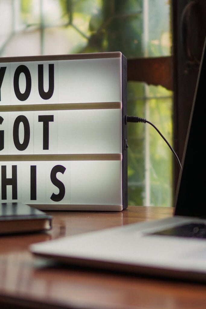 Lit sign with 'You Got This' alongside laptop on office desk.